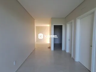 Foto de um corredor interno com paredes brancas e piso claro.