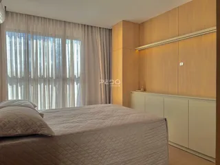 Quarto com cama e armários em madeira clara.