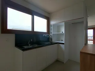 Vista da cozinha moderna com armários brancos e bancadas escuras.