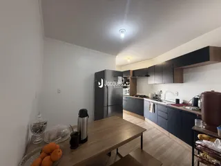 Cozinha moderna com armários escuros e piso de madeira clara.