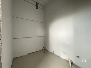 Foto de um interior com paredes brancas e piso em obra.