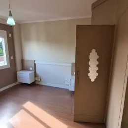 Foto interna de um corredor com parede clara e porta de madeira.