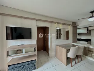 Sala de estar com televisão e móveis de madeira clara.