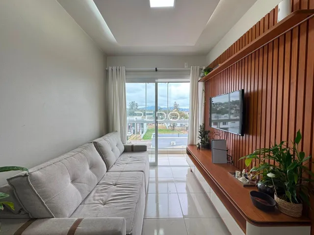 Sala de estar com sofá e porta de vidro que oferece uma vista externa.