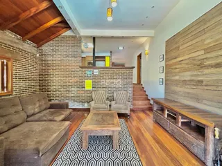 Sala de estar com piso de madeira e paredes de tijolo aparente.