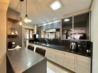 Imagem de uma cozinha moderna com armários e bancadas escuras.