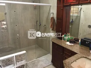 Banheiro com box de vidro e revestimento claro.