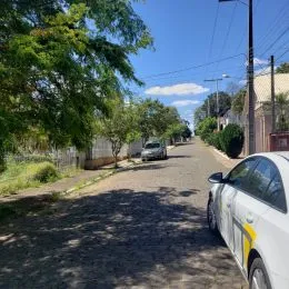 Vista de uma rua residencial em Lajeado, Brasil, com árvores e um carro estacionado.