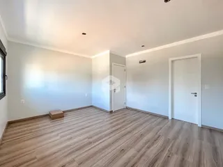 Ambiente interno de uma sala com piso de madeira clara e paredes brancas.