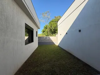 Vista externa de um terreno com paredes brancas e gramado.