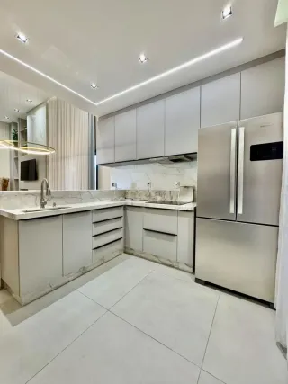 Cozinha moderna com armários brancos e bancadas claras.