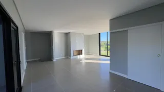 Sala ampla com piso de porcelanato e lareira, com vista para a paisagem externa.