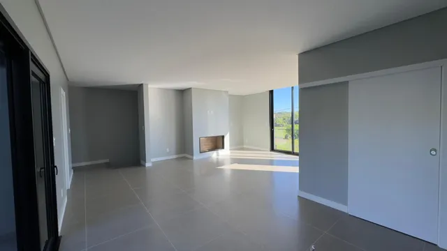 Sala ampla com piso de porcelanato e lareira, com vista para a paisagem externa.