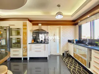 Cozinha moderna com armários brancos e bancadas escuras em um ambiente bem iluminado.