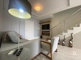 Vista de uma sala com escadaria e sofá.