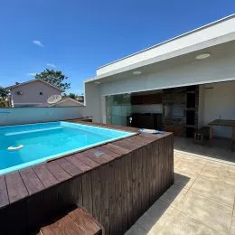 Piscina externa com deck de madeira em uma residência.