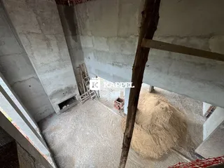 Foto de uma área em construção com vigas de madeira e concreto aparente.