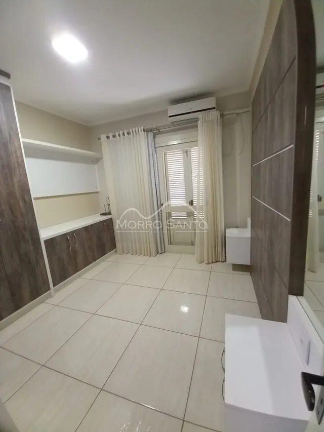 Hall de entrada com piso claro e cortinas brancas.