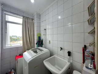 Foto de um banheiro com paredes de azulejo branco e janela.