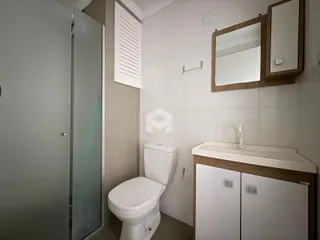 Banheiro com revestimento cerâmico e louças sanitárias brancas.