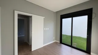 Vista de um corredor interno com porta de vidro que dá acesso a uma área externa gramada.
