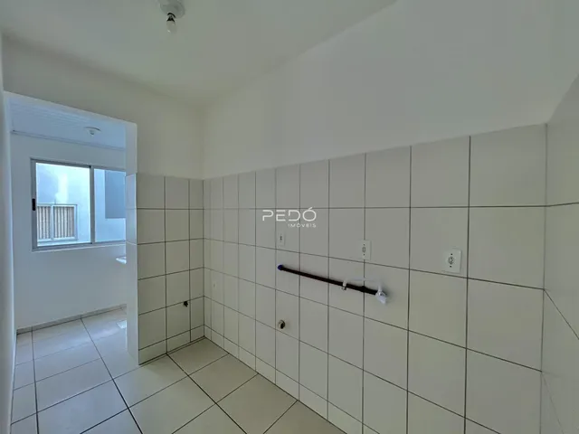 Hall de entrada com revestimento cerâmico branco nas paredes e piso.