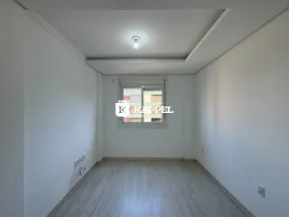 Uma sala de estar ampla com piso de madeira clara e janela no fundo.