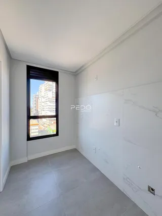 Interior de um ambiente com parede de mármore e grande janela.