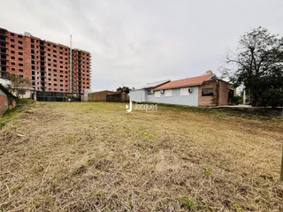 Vista externa de uma propriedade com terreno gramado e um edifício ao fundo.