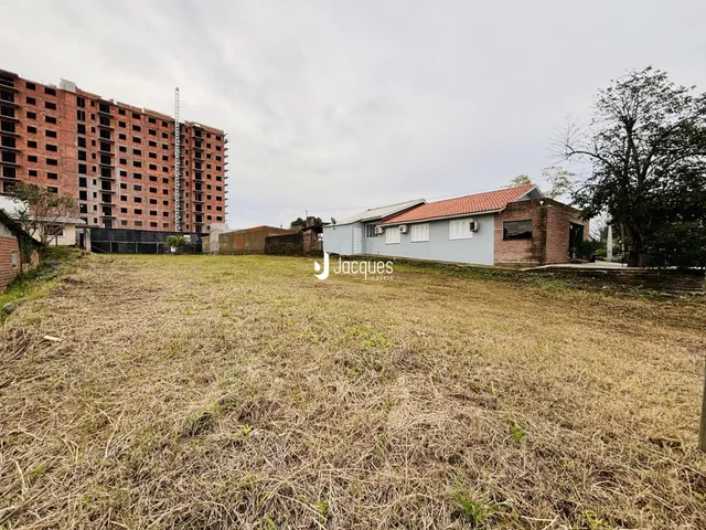Vista externa de uma propriedade com terreno gramado e um edifício ao fundo.