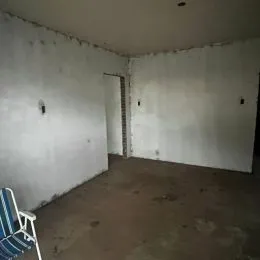 Foto de um cômodo interno com paredes brancas e piso de concreto.