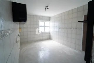 Uma sala com paredes revestidas de azulejos e piso de concreto.