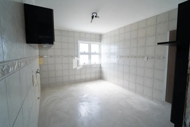 Uma sala com paredes revestidas de azulejos e piso de concreto.