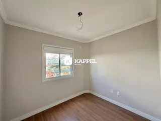 Ambiente interno com paredes brancas e piso de madeira, mostrando uma janela com vista para a cidade.