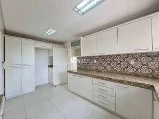 Uma cozinha com armários brancos e piso claro.