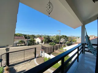 Vista de uma varanda com grade de ferro e piso cerâmico em uma residência no Brasil.