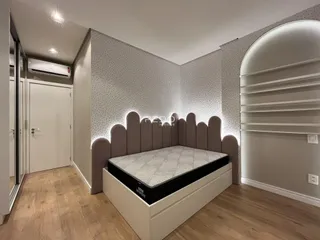 Quarto moderno com cama e cabeceira em um ambiente bem iluminado.