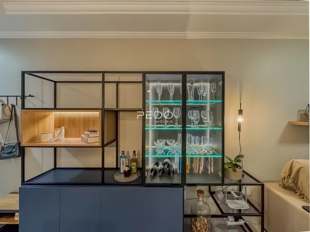 Uma estante de metal escura com portas de vidro decora o ambiente interno.