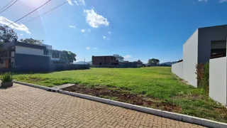 Vista externa de um terreno com gramado verde e paisagem sob um céu azul.