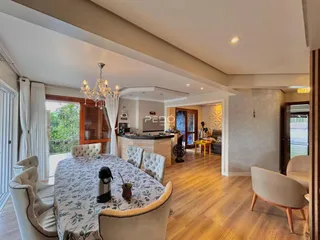 Ambiente interno de uma sala de jantar com piso de madeira clara.