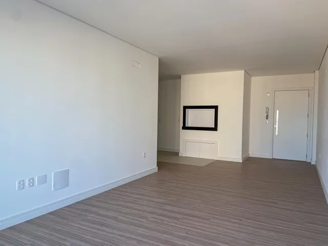 Hall de entrada com paredes brancas e piso de madeira clara.