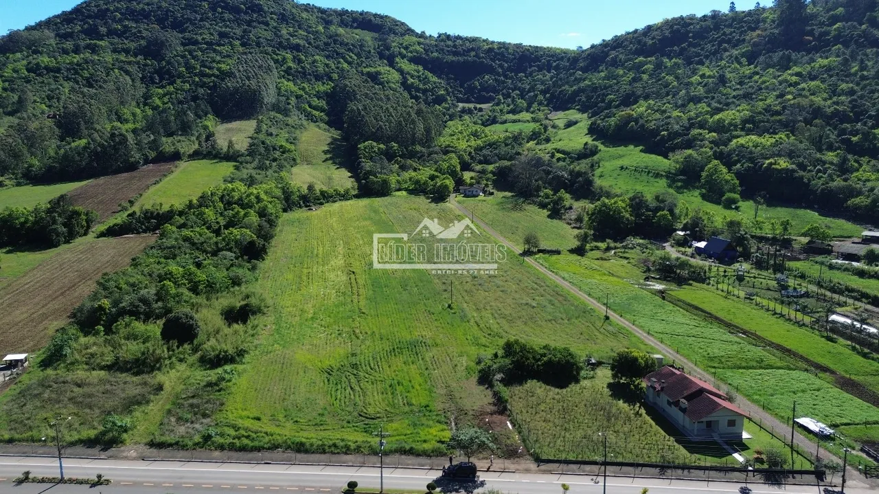 Vista aérea de paisagem rural com colinas arborizadas e campos verdes no Brasil.