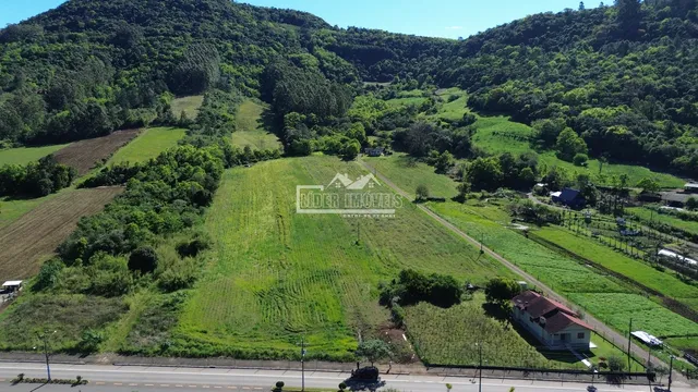Vista aérea de paisagem rural com colinas arborizadas e campos verdes no Brasil.