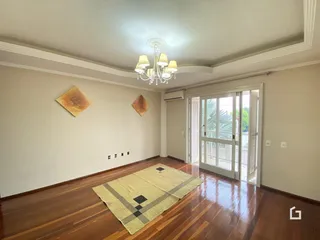 Sala de estar com piso de madeira e molduras brancas.