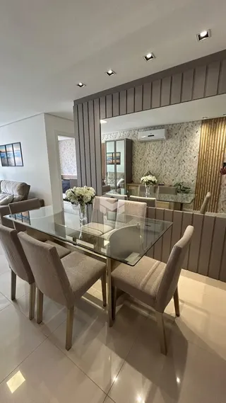 Sala de jantar com mesa de vidro e cadeiras estofadas.