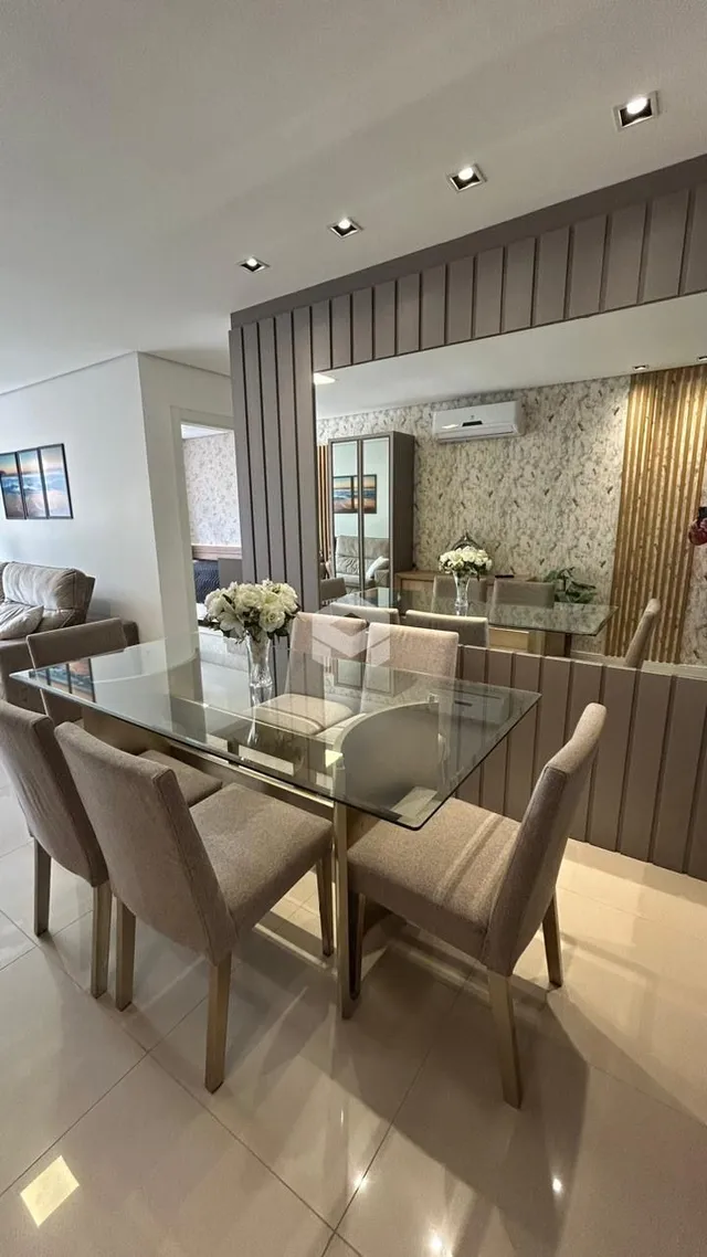 Sala de jantar com mesa de vidro e cadeiras estofadas.