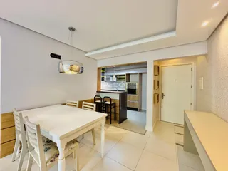 Uma sala de jantar com mesa e cadeiras brancas em um imóvel no Brasil.