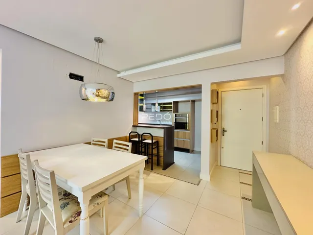 Uma sala de jantar com mesa e cadeiras brancas em um imóvel no Brasil.