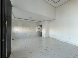 Ambiente interno amplo com piso de mármore branco e paredes brancas.
