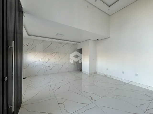 Ambiente interno amplo com piso de mármore branco e paredes brancas.